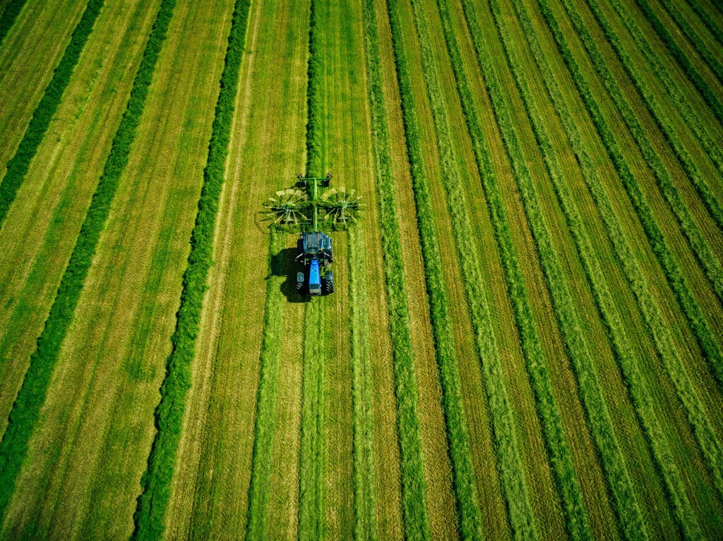 Aerial view of Tractor mowing green field in Finland.